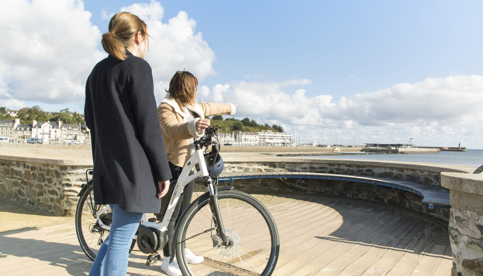 Deux femmes avec vélo sur la promenade de Binic, Bretagne, France.