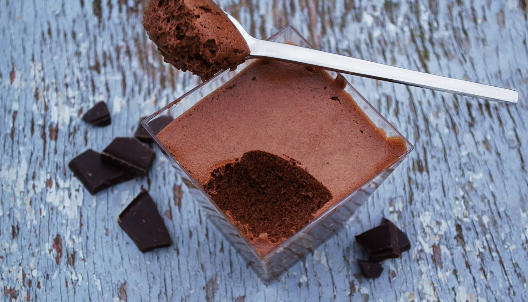Chocolat mousse dans un verre avec cuillère et morceaux de chocolat noir.